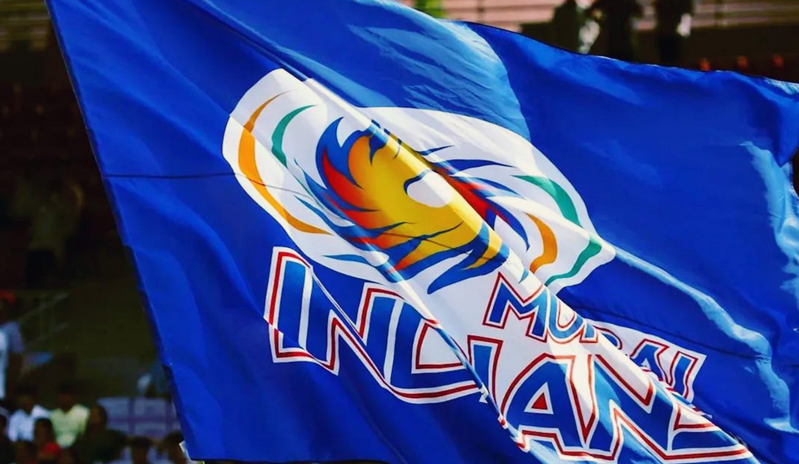 Fans waving the vibrant Mumbai Indians flag at a packed stadium, showcasing their unwavering support for their beloved IPL team